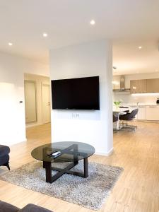 ein Wohnzimmer mit einem Tisch und einem TV an der Wand in der Unterkunft G Apartment in Podstrana