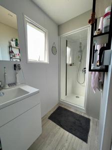 La salle de bains blanche est pourvue d'une douche et d'un lavabo. dans l'établissement Mobil Home superbe Vue Mer St Raphaël, à Saint-Raphaël