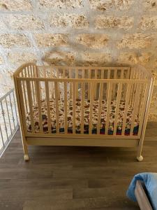 een houten wieg in een kamer met een bakstenen muur bij Locazione Santa Rita in Molfetta