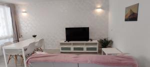 sala de estar con TV y mesa con sillas en Ideal holiday apartment in the south of Tenerife en Costa del Silencio