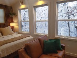 een slaapkamer met een bed, een bank en drie ramen bij Emerald Little Lodge in Elroy
