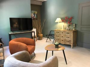 a living room with two chairs and a flat screen tv at Le Clos du Peintre in Sarlat-la-Canéda