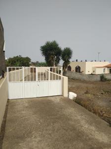 a white fence in front of a building with palm trees at Casa Rural Aguarijo in Mocanal