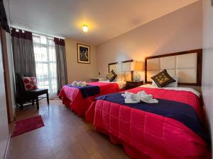 Chikan Hoteles في أريكيبا: سريرين في غرفة الفندق باللونين الأحمر والأزرق
