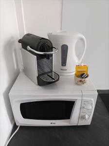 a white microwave sitting on a counter with a coffee maker at O'Couvent - Appartement 73 m2 - 2 chambres - A311 in Salins-les-Bains