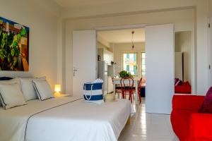 a bedroom with a white bed and a red chair at La Casa Di Stefe in Giardini Naxos