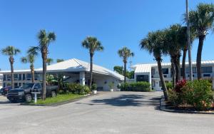 a building with palm trees in front of a parking lot at Village Inn Destin in Destin