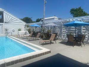 eine Terrasse mit Stühlen und Sonnenschirmen neben einem Pool in der Unterkunft Village Inn Destin in Destin