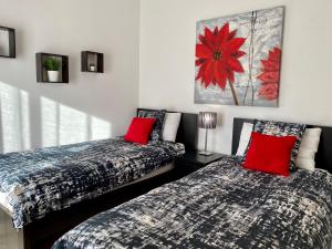 um quarto com 2 camas com almofadas vermelhas e um quadro em Blue Sky apartment Marina em Lagos