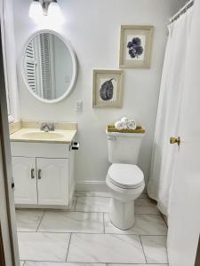 Un baño con inodoro, lavabo y espejo. en Blue Water Inn, en Ocean City