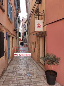 an alley with a sign that says we are here at Old Town Apartments in Rovinj