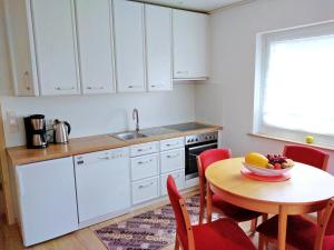 a kitchen with white cabinets and a table with a bowl of fruit at Helena Ferienwohnung in Hemfurth-Edersee