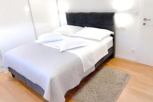 ein weißes Bett mit einem schwarzen Kopfteil und einem Teppich in der Unterkunft G Apartment in Podstrana