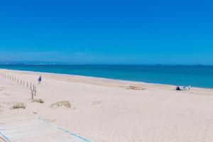 a beach with people sitting on the sand and the ocean at Salamar Saler Golf in El Saler