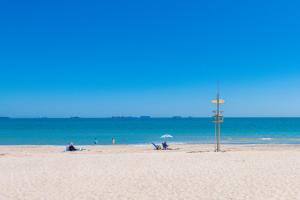 a beach with people sitting on the sand and the ocean at Salamar Saler Golf in El Saler