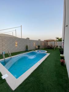 ein Pool in einem Garten mit grünem Gras in der Unterkunft ALZumorod Luxury Villa in Ma‘ābīlah