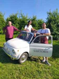 un grupo de personas de pie junto a un pequeño coche en Poderi Sartoris, en San Marzano Oliveto
