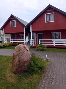 a red house with a large rock in front of it at Agromarko in Ustronie Morskie