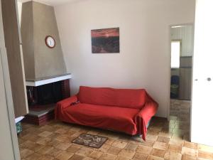 un sofá rojo en la sala de estar con chimenea en Villa Colaiuta, en Ostuni