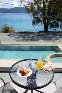 una mesa con un plato de comida y un vaso de zumo de naranja en ALMYRA seafront residence, en Ligia