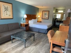 デスティンにあるVillage Inn Destinのベッド、ソファ、テーブルが備わるホテルルームです。