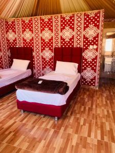 a room with two beds and a red wall at WADI RUM-Bedouin Tents and Jeep Tours in Wadi Rum