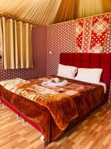 um quarto com uma cama grande e uma parede vermelha em WADI RUM-Bedouin Tents and Jeep Tours em Wadi Rum