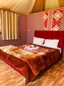 a bedroom with a large bed with a red wall at WADI RUM-Bedouin Tents and Jeep Tours in Wadi Rum +43 photos