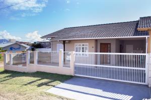 a white fence in front of a house at Recanto do Mar Pinheira in Palhoça