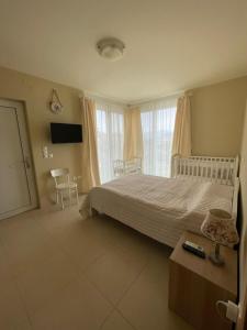 sypialnia z białym łóżkiem, telewizorem i oknem w obiekcie Villa Natalia w mieście Tolo