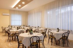 una stanza piena di tavoli e sedie con tovaglia bianca di Hotel Giordo a Rimini