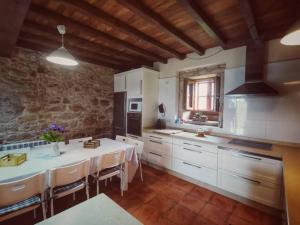 a kitchen with a table and a kitchen with white cabinets at Casa do Peto in A Bana