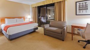 a bedroom with a bed and a chair and a desk at Best Western Plus Bayside Inn in San Diego