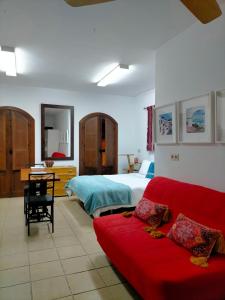 a living room with a red couch and a bed at Centro de Arte in Yunquera