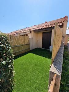 einen kleinen Hinterhof mit einem Garten mit grünem Gras in der Unterkunft Villa bord de mer avec belle terrasse in Port Leucate