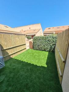 einen Hof mit grünem Gras und einem Zaun in der Unterkunft Villa bord de mer avec belle terrasse in Port Leucate