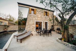 patio ze stołem i krzesłami oraz budynek w obiekcie Casa Giulia with heated pool w mieście Privlaka