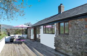 a house with a wooden deck with a table and an umbrella at The Neuadd Cottages in Crickhowell