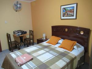 a bedroom with a bed and a table with a fan at Kurmi Hostel Lima Airport in Lima