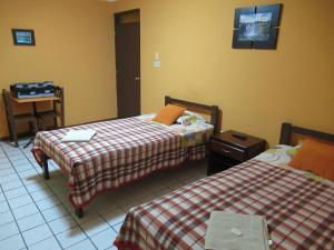 Kurmi Hostel Lima Airport في ليما: غرفة فندقية بسريرين وطاولة