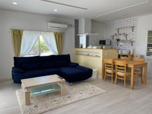 ein Wohnzimmer mit einem blauen Sofa und einem Tisch in der Unterkunft Holiday Villa 旅生 in Tonosho