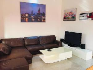 a living room with a brown leather couch and a tv at Villa Cocotiers A11 in Cotonou