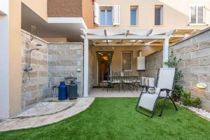 een patio met gras en stoelen voor een huis bij Casa Helen in SantʼAntìoco