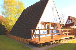 una casa con techo negro y terraza de madera en Ferienhaus Lüttje Swaan, en Detern