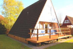 a house with a black roof and a wooden deck at Ferienhaus Lüttje Swaan in Detern