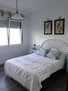 a white bed in a white bedroom with two windows at RIA DE BELUSO in Bueu