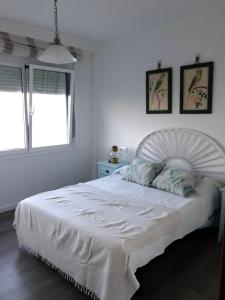 a white bed in a white bedroom with two windows at RIA mar DE BELUSO in Bueu