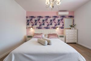 a bedroom with a large white bed with pink walls at Villa Boro 3 in Dubrovnik
