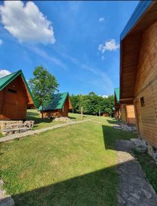 a group of wooden buildings with a grass yard at Grand Tara Rafting Resort in Foča