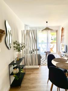 a living room with a table and some chairs at L'Escapade Bohème - piscine, plages & farniente in La Grande Motte